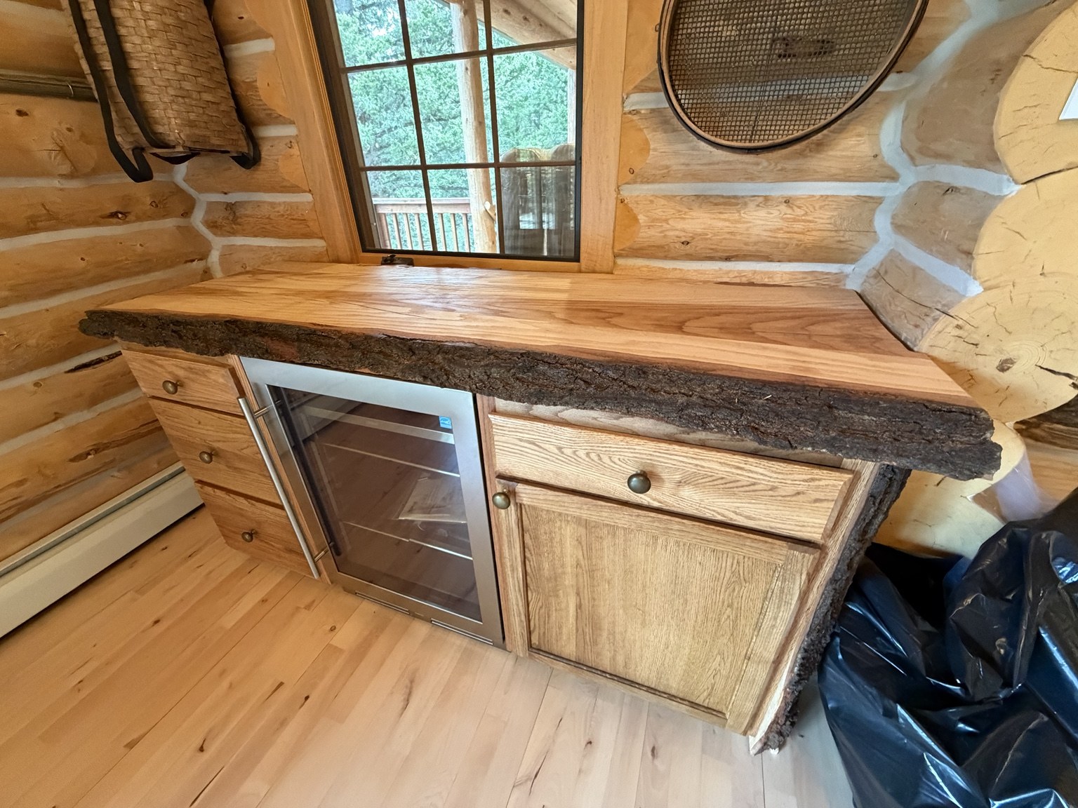 Rustic wood bar cabinetry and beverage refrigerator in a log cabin