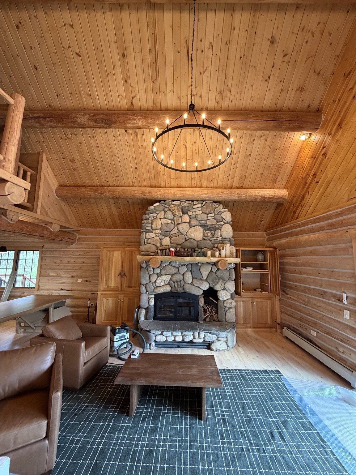 Log cabin living room with stone fireplace and wood ceiling
